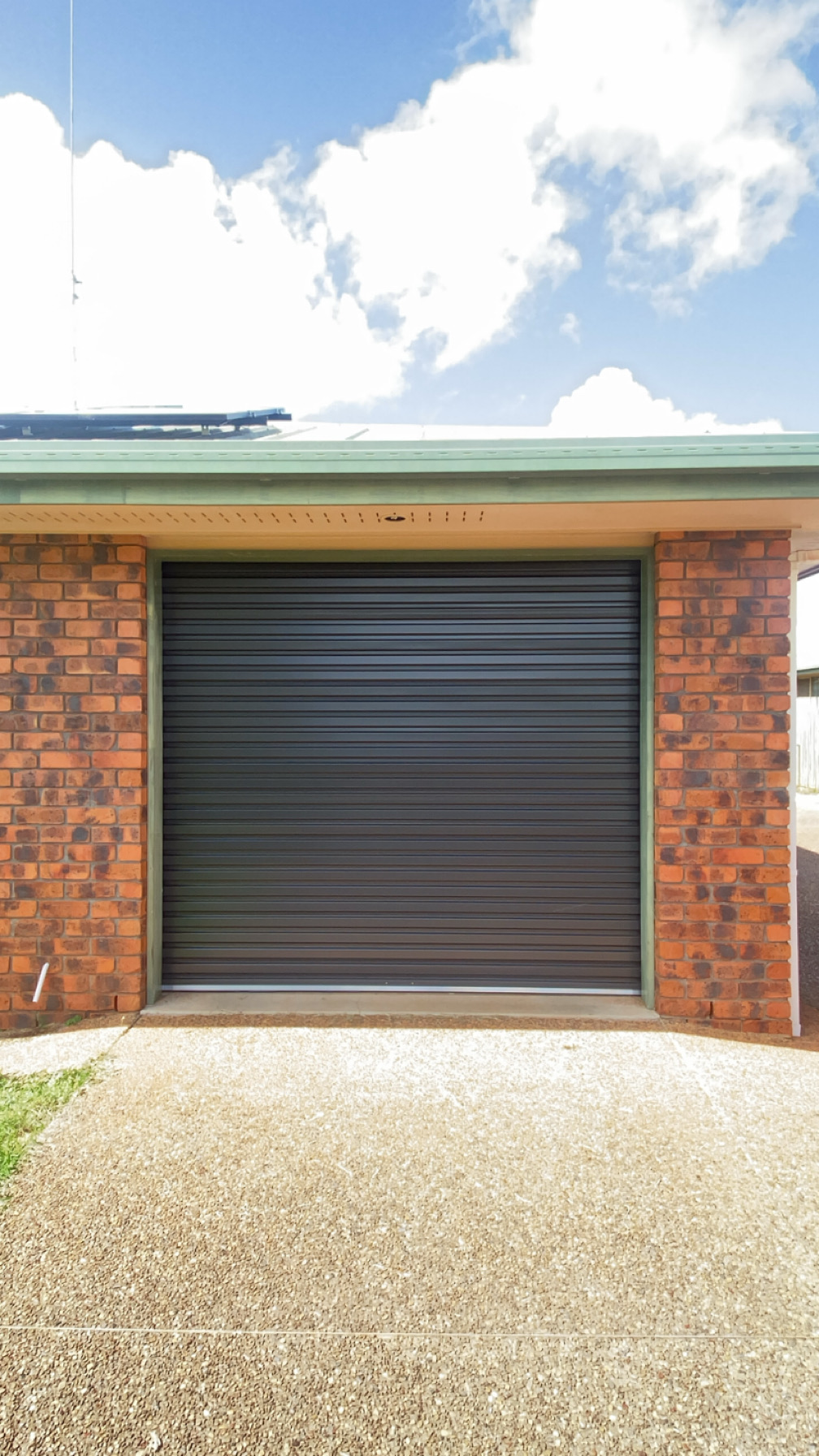Charcoal residential roller door installed in a brick home